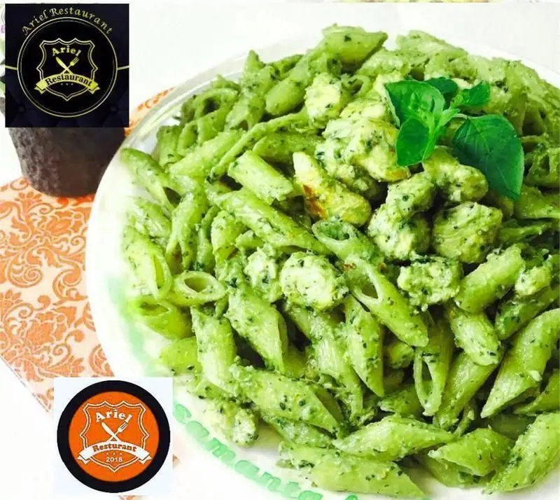 پاستا پنه سبز با سس پستو، تکه های مرغ و برگ ریحان تازه در بشقاب سفید. یک غذای لذیذ ایتالیایی از رستوران فرنگی آریل.
