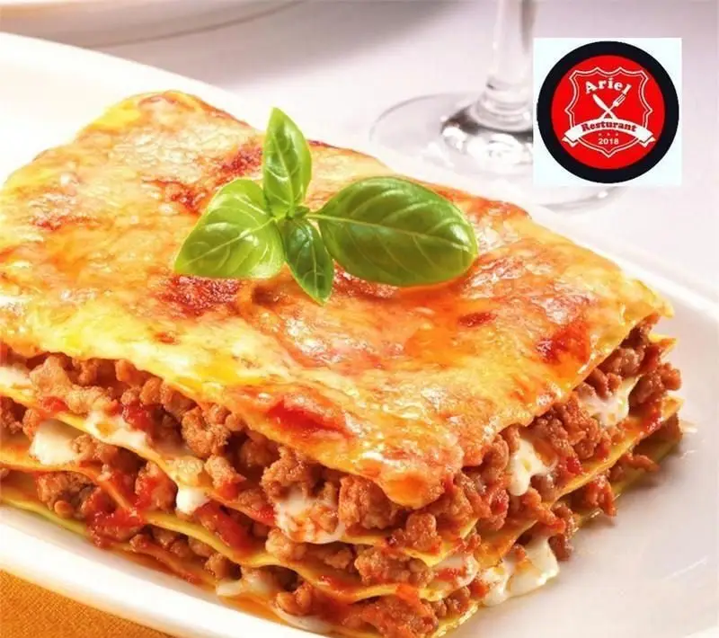 لازانیا لذیذ رستوران فرنگی آریل با لایه‌های گوشت، سس گوجه و پنیر آب شده، تزئین شده با ریحان تازه، غذای ایتالیایی عالی.