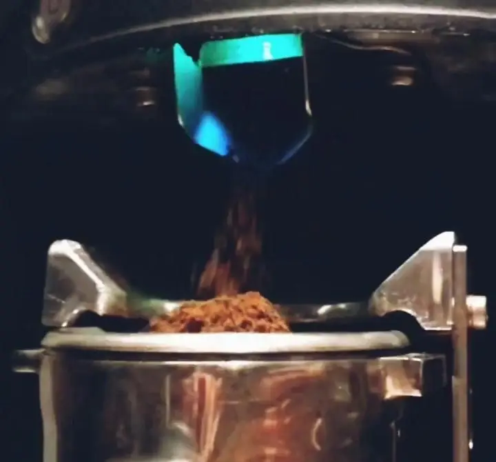 پودر قهوه تازه آسیاب شده از دستگاه آسیاب در حال ریختن درون پرتافیلتر برای آمادهسازی قهوه در نان روستار. لذت قهوه تازه.