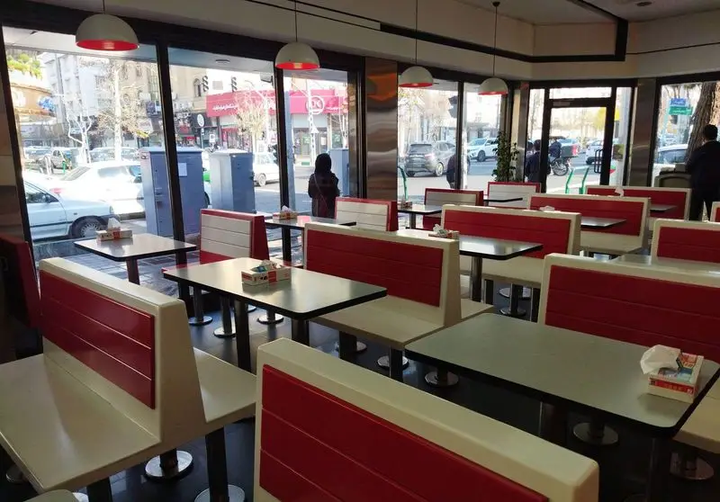 فضای داخلی دنج و مدرن پیتزا زرین با چیدمان میز و صندلی‌های قرمز و سفید، مناسب برای لذت بردن از پیتزا و غذاهای خوشمزه.