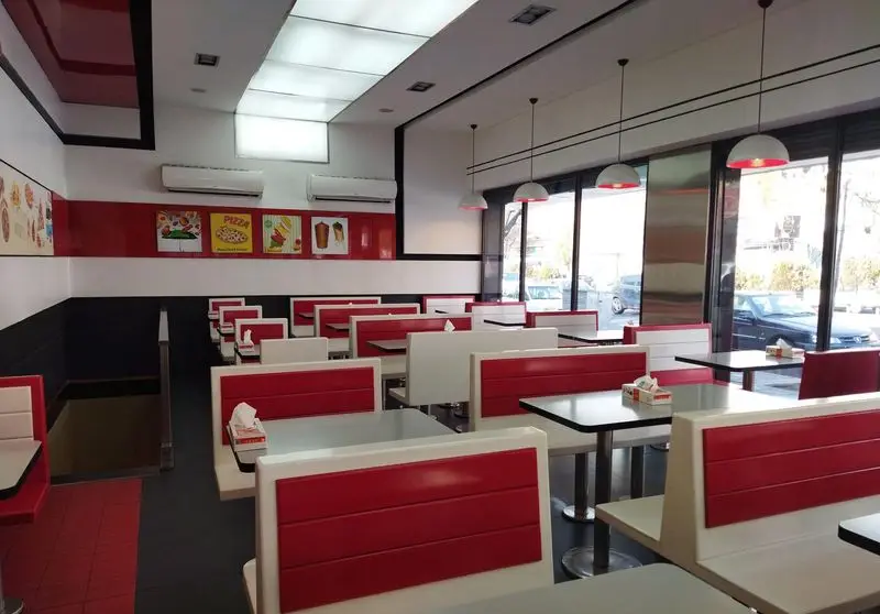 فضای داخلی شیک و تمیز رستوران پیتزا زرین با دکوراسیون مدرن قرمز، سفید و مشکی، میز و صندلی‌های راحت برای مشتریان.