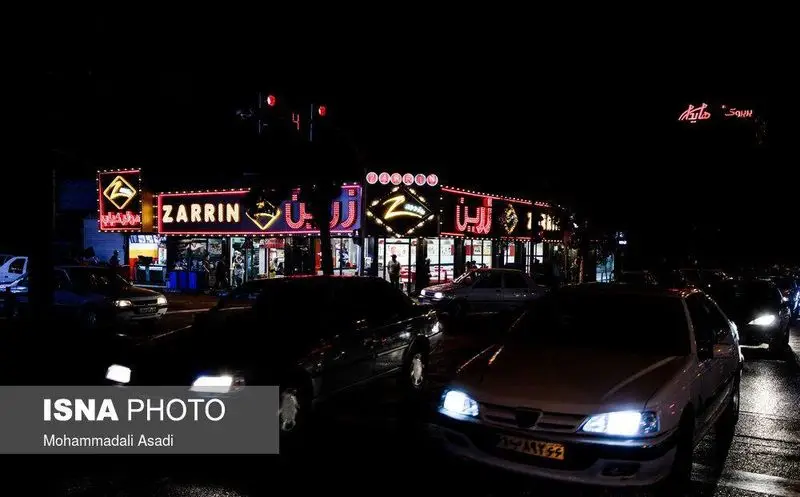 نمای شبانه پیتزا زرین با نورپردازی روشن و زیبا، خیابان شلوغ با خودروها در حال تردد. تجربه‌ای دلنشین از شهر در شب.