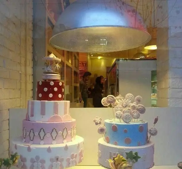 ویترین کافه قنادی ورتا با انواع کیک‌های سفارشی و زیبای عروسی و تولد. نمایش کیک‌های چند طبقه و دکوراسیون خاص شیرینی‌فروشی.