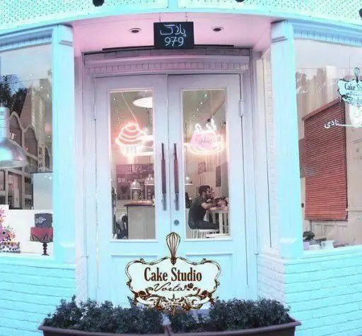 نمای بیرونی کافه قنادی ورتا و کیک استودیو با پلاک ۹۷۹. ورودی جذاب و مدرن، نمایش ویترین کیک و شیرینی، با نورپردازی نئونی.