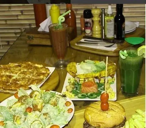 میز پر از غذاهای متنوع و خوشمزه رستوران پیروک شامل پای بزرگ، سالاد سزار، همبرگر ویژه و نوشیدنی‌های تازه و جذاب.