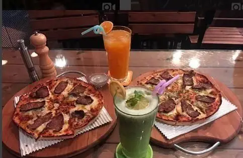 دو پیتزای مخصوص گوشت با پنیر فراوان و نوشیدنی‌های پرتقالی و نعنایی تازه در محیط دلنشین و مدرن رستوران پیروک.