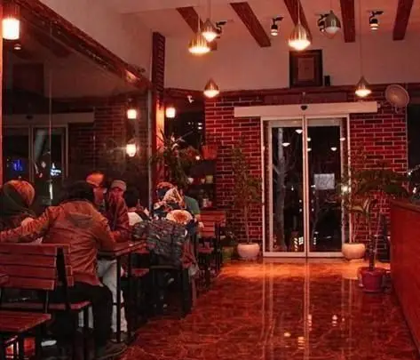 نمای داخلی زیبای کافه رستوران پیروک با دکوراسیون آجر قرمز، سقف چوبی، نورپردازی گرم و دلنشین، فضایی دنج برای مشتریان.