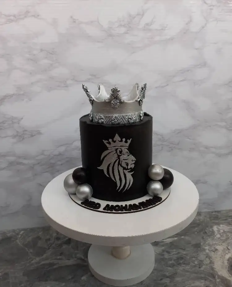 کیک تولد مردانه لاکچری مشکی و نقره‌ای با طرح شیر و تاج سلطنتی، مناسب سفارش کیک خاص در فینگرفود تهران خاورشهر.
