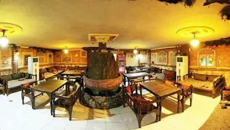 فضای داخلی سفره خانه چار دیواری با طراحی سنتی و دلنشین، میز و صندلی چوبی و تخت‌های راحت، مکانی ایده‌آل برای دورهمی خانوادگی.