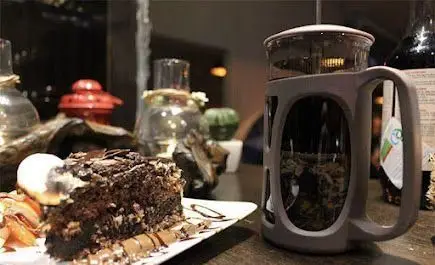 برشی از کیک شکلاتی غنی با بستنی و دمنوش چای تازه در کافه موگه، تجربه‌ای شیرین و دلنشین در یک عصر دلپذیر.