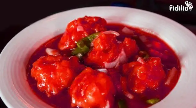 غذای چینی دلپذیر با سس قرمز تند یا شیرین، شامل تکه‌های مرغ یا قارچ، پیاز و فلفل سبز در کاسه‌ای سفید. از منوی رستوران چینی اژدهای طلایی.