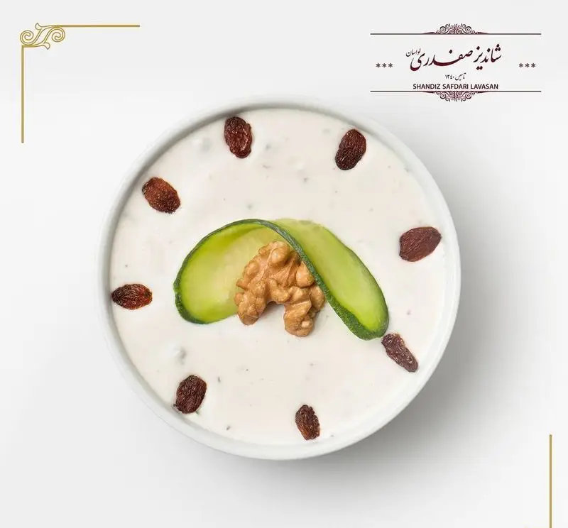 تصویری جذاب از ماست و خیار رستوران شاندیز صفدری لواسان، با گردو و کشمش به شکل ساعت، یک پیش‌غذای ایرانی خاص.