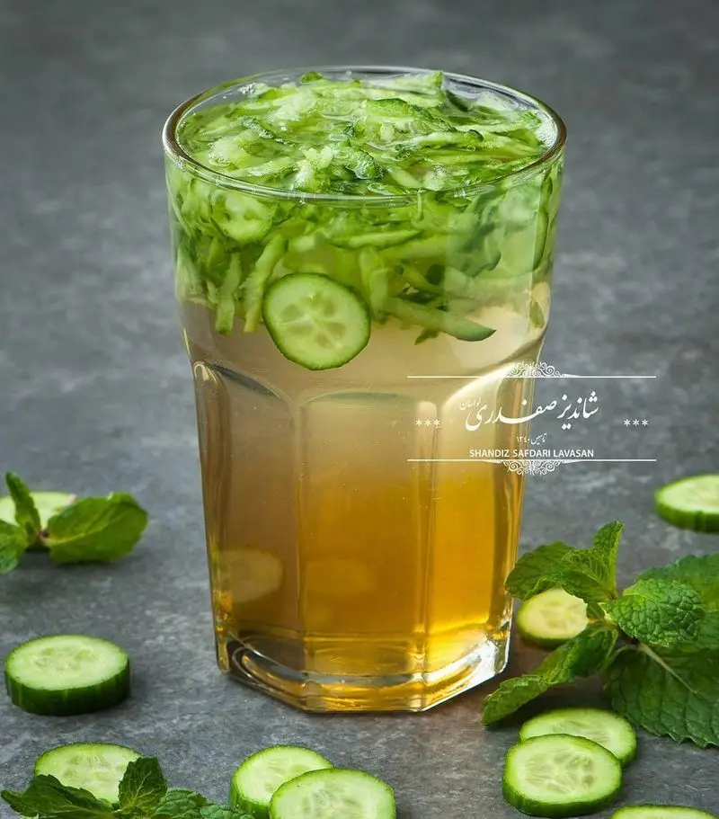 لیوانی از نوشیدنی خنک تابستانی خیار و نعناع، با تکه‌های فراوان خیار خرد شده، اثری از منوی جذاب رستوران شاندیز صفدری لواسان.