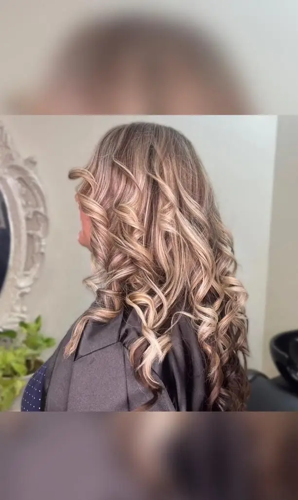 بالیاژ بلوند و خاکستری روی موهای بلند و فر شده در آرایشگاه زنانه آنا، مدلی شیک و مدرن برای خانم‌های خوش‌سلیقه.