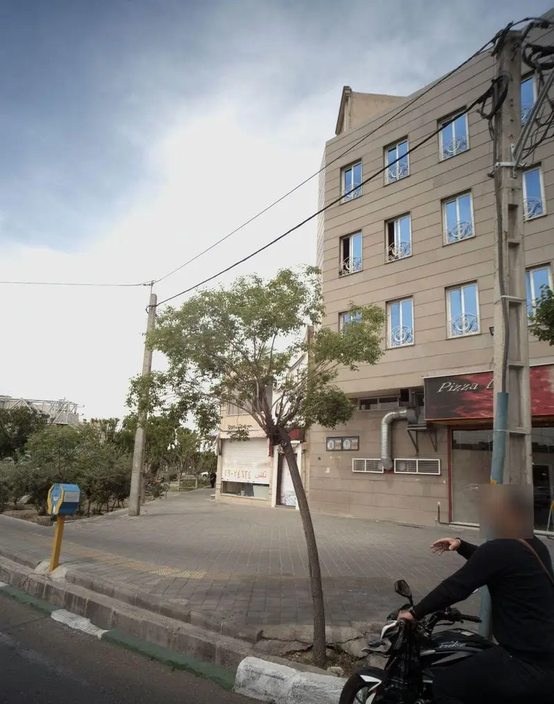 نمایی واقعی از ساختمان رستوران فست فود پیتزا دنج در کنار پیاده رو شلوغ شهر، شامل جزئیات ورودی و علائم تجاری.