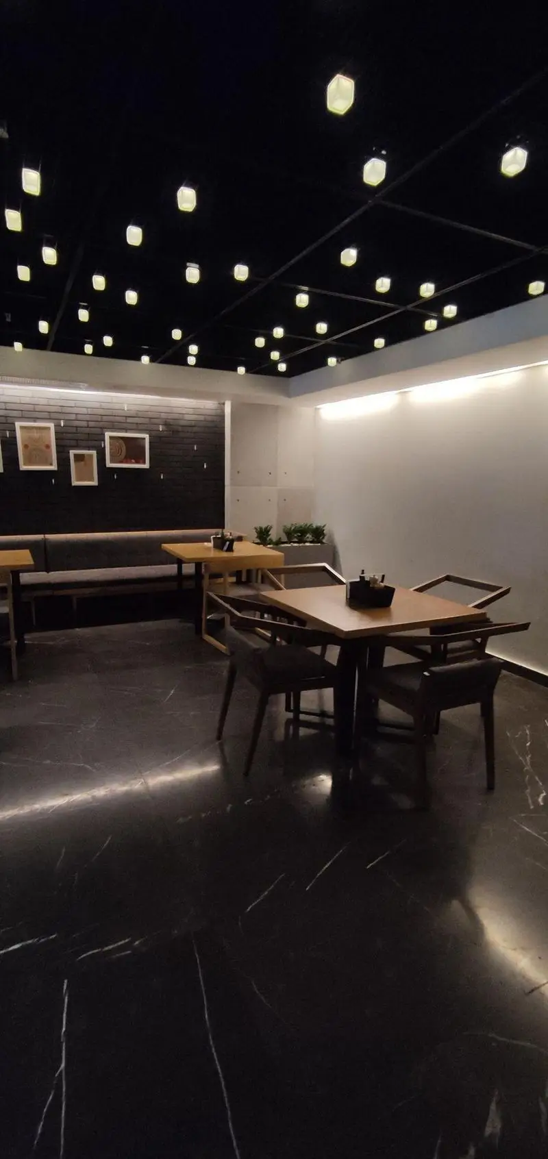 فضای داخلی شیک و مدرن فست فود دکتر آرین با نورپردازی منحصر به فرد سقف تیره و میزهای چوبی. محیطی آرام و دلپذیر.