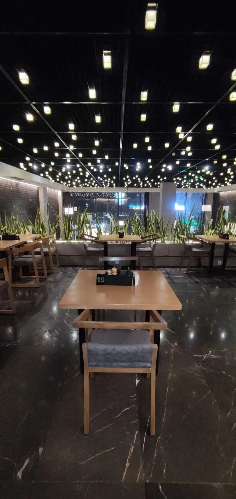 فضای داخلی رستوران و فست فود دکتر آرین با دکوراسیون شیک و نورپردازی مدرن، میزهای چوبی و گیاهان طبیعی برای محیطی آرام و دلنشین.