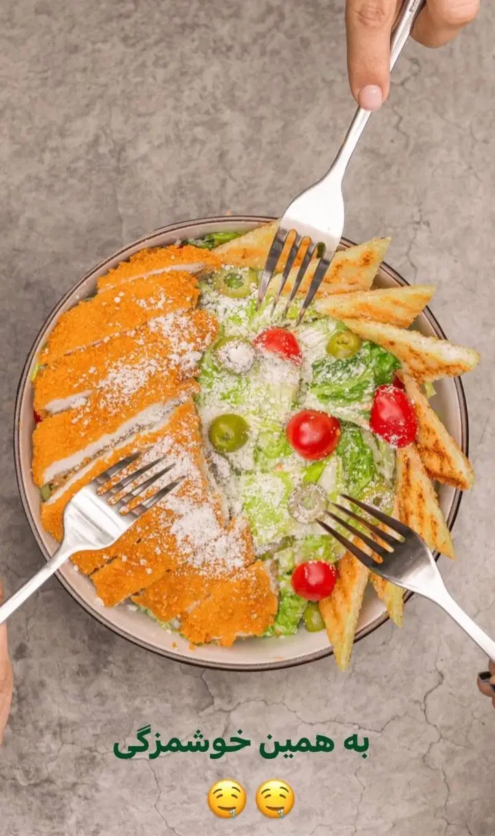 سالاد سزار مرغ سوخاری کافه رام بیسترو با نان تست طلایی، زیتون و گوجه، آماده سرو؛ غذای لذیذ و دلپذیر در رستوران.