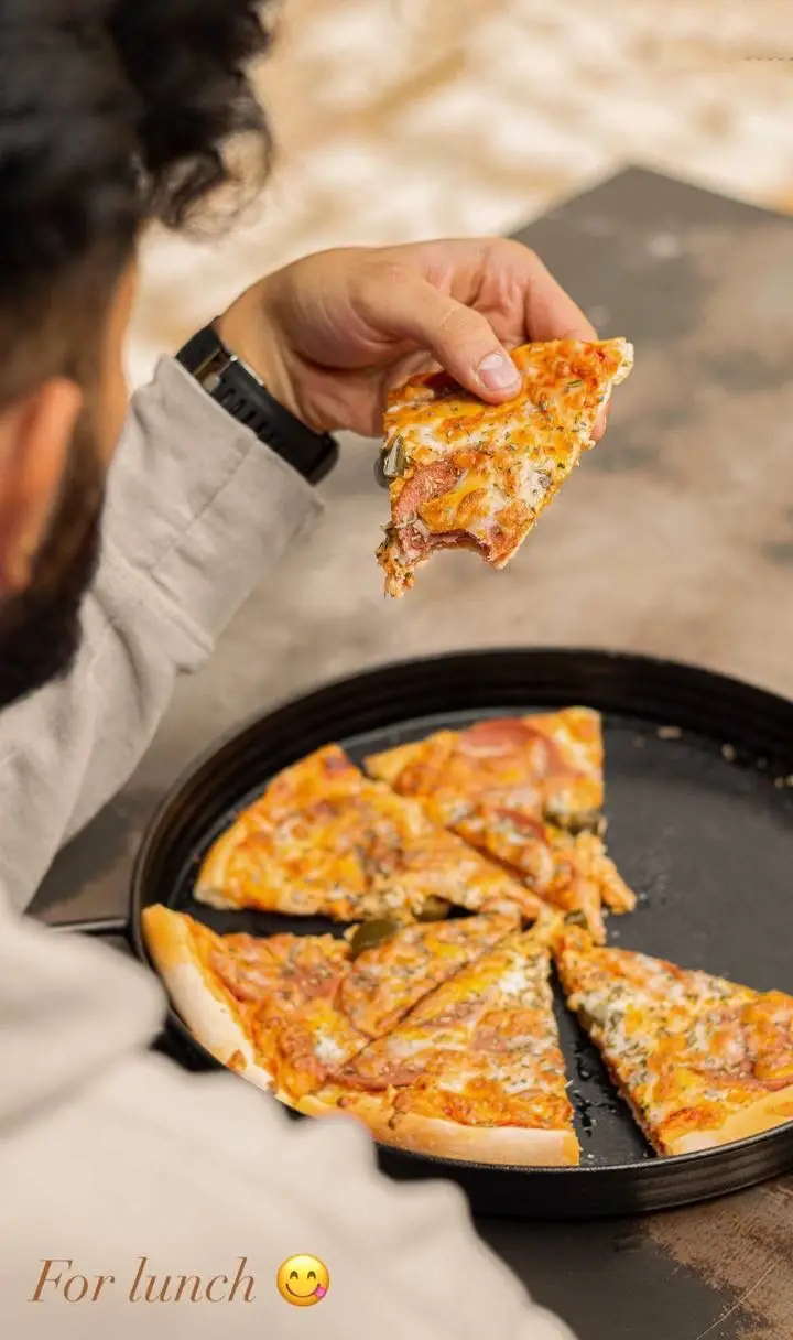 یک برش پیتزای تازه و داغ از کافه رام بیسترو. ایده‌آل برای ناهار و تجربه طعم لذیذ غذاهای متنوع همراه با نوشیدنی‌های دلخواه.