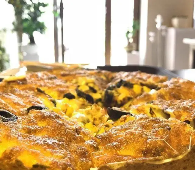 تصویری نزدیک از املت یا کوکو طلایی و خوشمزه پیتزایی طلوع با تکه های زیتون و سبزیجات، مناسب برای صبحانه.