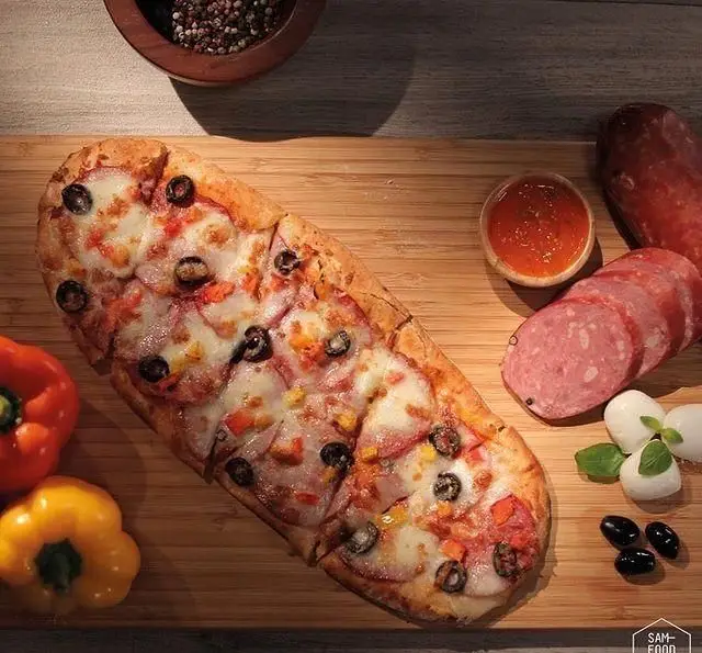 پیتزا لقمه ای جذاب فودهال سام با پپرونی، پنیر و زیتون. روی تخته چوبی همراه با سوسیس، موزارلا و فلفل دلمه ای برای تجربه ای دلپذیر.