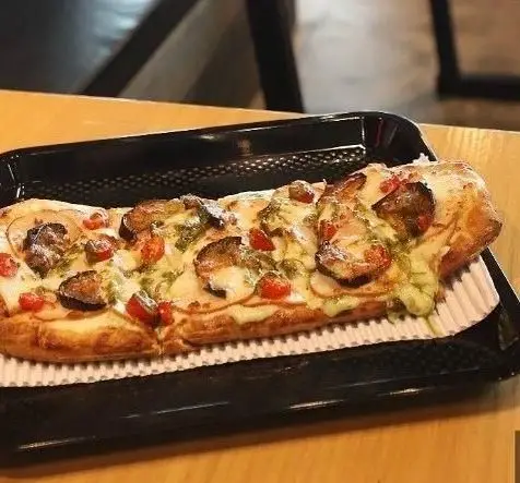 پیتزا مستطیلی کشیده و تازه با پنیر ذوب شده، قارچ، گوجه گیلاسی و سس پستو در فودهال سام. یک تجربه طعم بی‌نظیر.