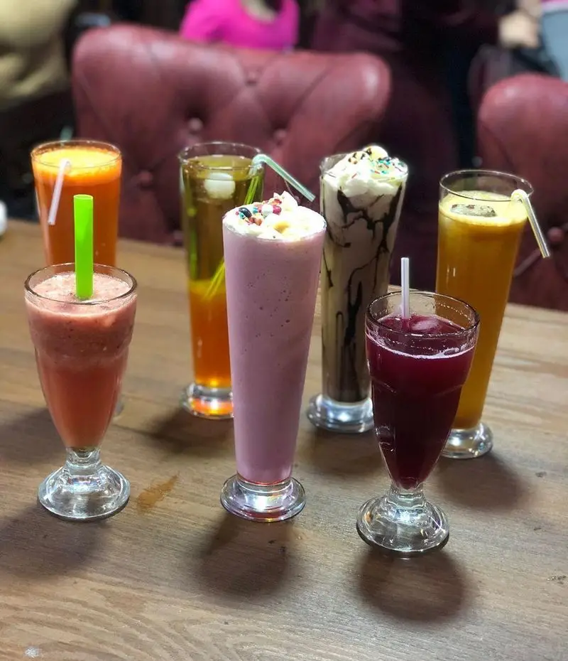 مجموعه‌ای از نوشیدنی‌های خنک و تازه: آبمیوه‌های میوه‌ای، شیک و اسموتی رنگارنگ در سفره خانه سنتی دیزی نار، تجربه‌ای لذت‌بخش در محیطی دنج.