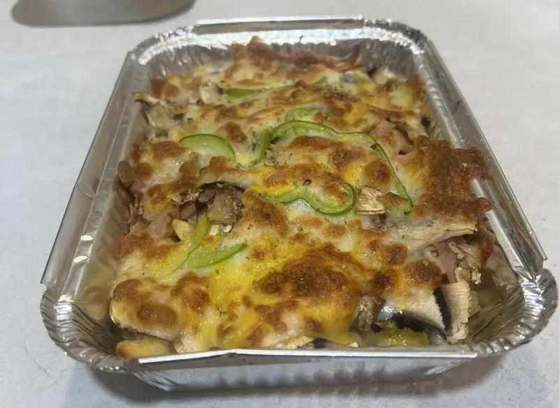 پیتزا بیک قارچ و فلفل دلمه ای داغ از پی پزا، با پنیر فراوان و طلایی در سینی آلومینیومی، آماده ارسال و سرو.