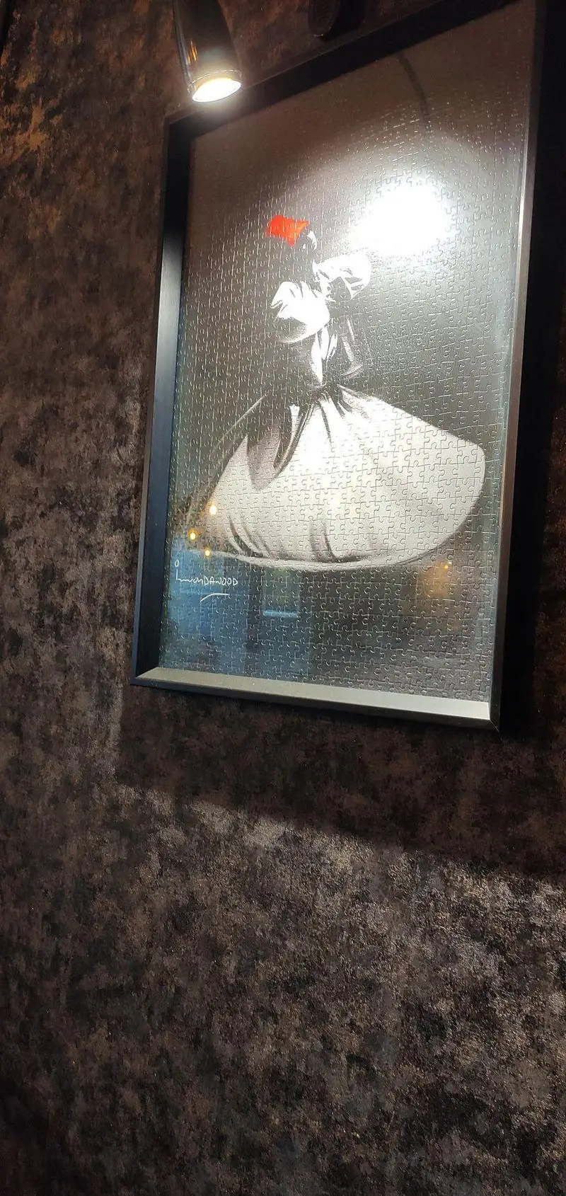 پازل قاب‌شده با طرح درویش چرخان و کلاه قرمز، از تزئینات جذاب کافه پازل با نورپردازی روی دیوار.