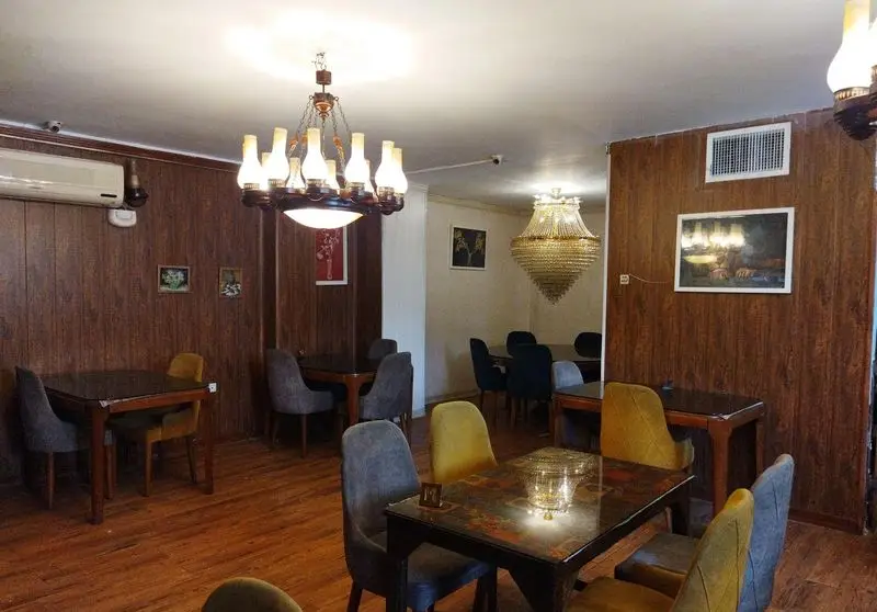 نمای داخلی زیبای کافه برنا، با دیوارپوش های چوبی، لوسترهای چشمگیر، و میز و صندلی های راحت در فضایی دلنشین.