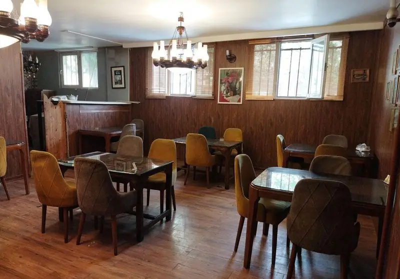 فضای داخلی کافه برنا با دکوراسیون چوبی، میز و صندلی‌های راحتی، محیطی دنج و سنتی برای مشتریان فراهم کرده است.