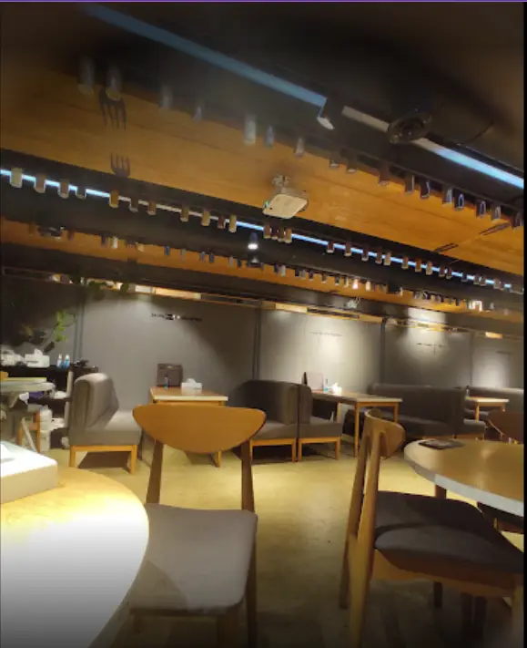 فضای داخلی آرام و دلنشین سرزمین سوخاری، شامل میز و صندلی‌های چوبی و مبلمان راحتی با نورپردازی گرم و سقف تزئینی.