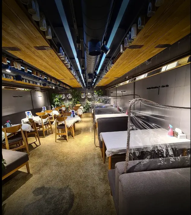 فضای داخلی مدرن و جذاب رستوران سرزمین سوخاری با دکوراسیون چوبی، سقف صنعتی، میز و صندلی‌های شیک و رعایت پروتکل‌های بهداشتی.