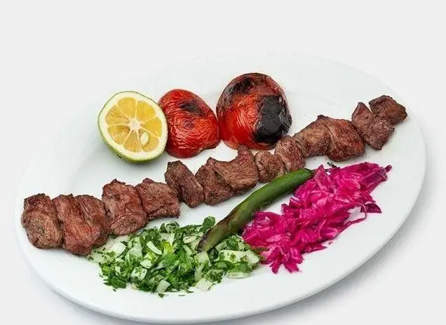 بشقاب کباب گوشت تازه و خوش طعم کبابی صادق گلپایگانی همراه با گوجه کبابی، لیمو، سبزی معطر و سالاد کلم، یک وعده کامل ایرانی.