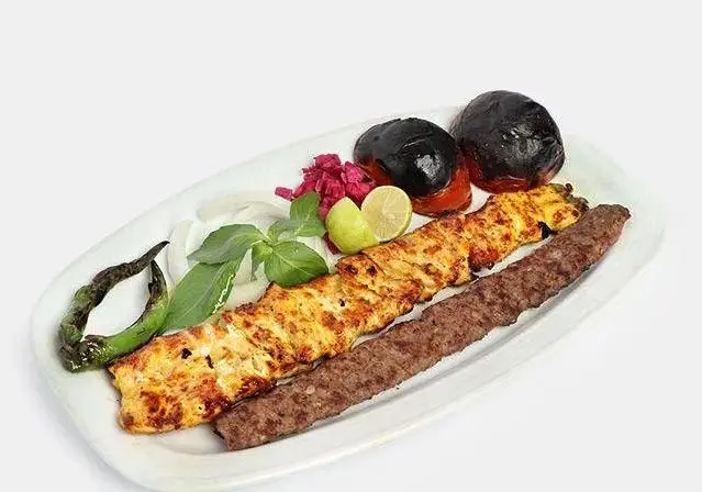 سینی کباب کوبیده و جوجه کباب مجلسی با مخلفات تازه شامل گوجه کبابی، پیاز، ریحان، فلفل و لیمو از کبابی صادق گلپایگانی.