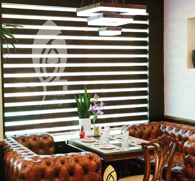 دکوراسیون داخلی کافه رستوران بام ری با مبلمان چرمی شیک، پرده زبرا مدرن و نورپردازی گرم، فضایی دلنشین برای مشتریان.