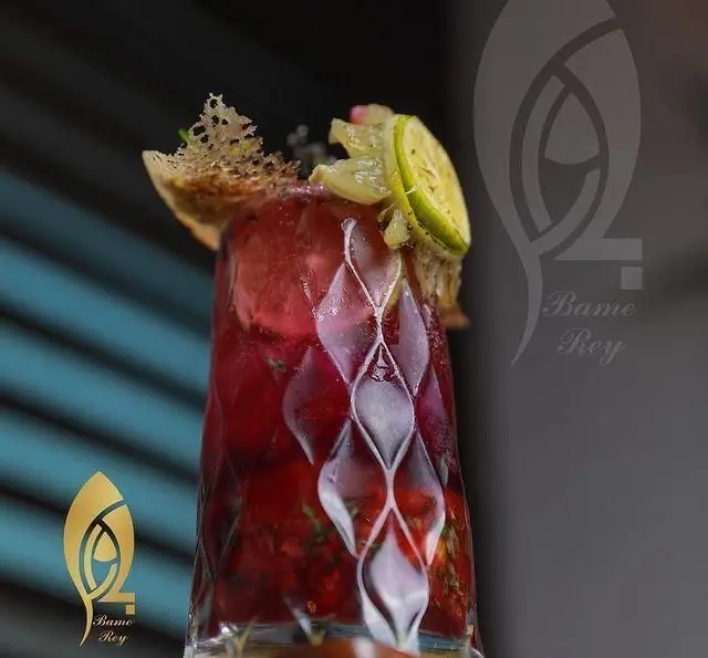 نوشیدنی خنک و خوشمزه در کافه رستوران بام ری. یک کوکتل میوه‌ای جذاب با برش‌های لیمو و دیزاین خاص در لیوانی شیک.