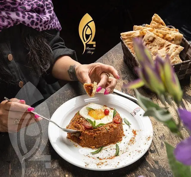 لذت بردن مشتری از غذای لذیذ در کافه رستوران بام ری، با نان تازه و تخم مرغ عسلی. تجربه‌ای دلنشین و باکیفیت.