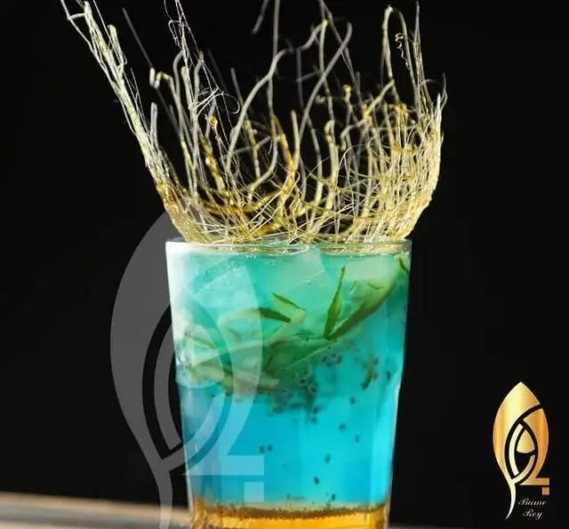 نوشیدنی آبی رنگ خاص کافه رستوران بام ری با تزئین هنری کارامل طلایی، تخم شربتی و برگ‌های سبز، ارائه دهنده تجربه‌ای متفاوت و لوکس.