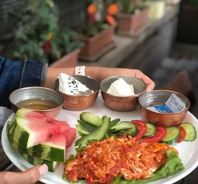 میز صبحانه کامل و خوش‌رنگ رستوران درخت ژینکو با منمن، پنیرهای متنوع، عسل، هندوانه تازه و سبزیجات. تجربه‌ای دلنشین و مغذی.