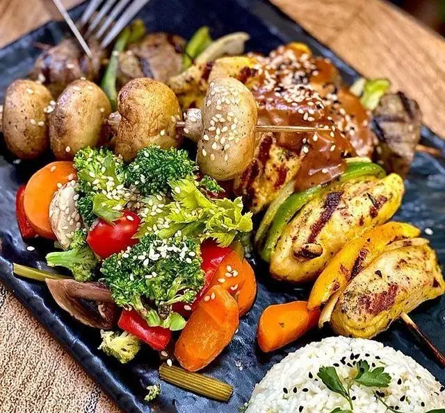 بشقاب غذای سالم و لذیذ رستوران درخت ژینکو: کباب چوبی مرغ و قارچ گریل، سبزیجات تازه، برنج و سس مخصوص. ایده‌آل برای رژیم غذایی.