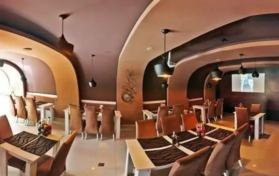 فضای داخلی دلنشین و مدرن رستوران درخت ژینکو با میز و صندلی‌های شیک، سقف‌های منحنی و نورپردازی گرم، محیطی عالی برای غذاخوری.