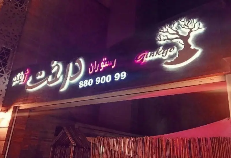تابلوی درخشان رستوران درخت ژینکو با لوگوی خلاقانه درخت و چهره، نوشته 'Ginkyo' و شماره تلفن 88090099.