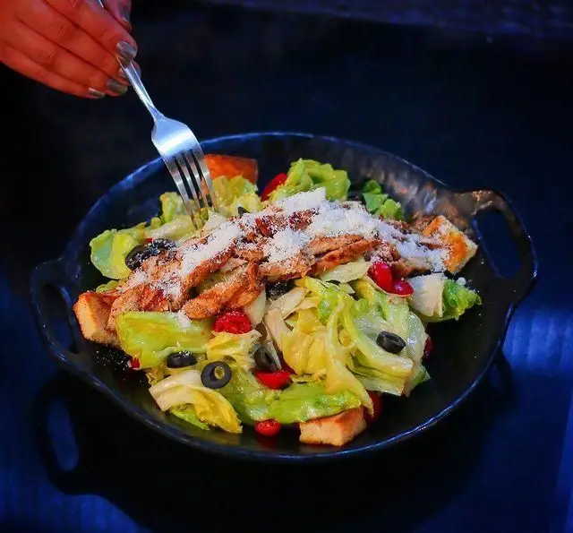 سالاد سزار مرغ تازه و خوشمزه رستوران درخت ژینکو با کاهو، مرغ گریل، نان کروتون، زیتون سیاه و پنیر پارمزان، غذایی سالم و لذیذ.