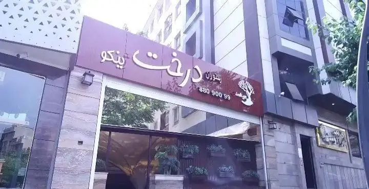 تصویری از نمای خارجی رستوران درخت ژینکو با تابلوی مشخص، لوگوی درخت ژینکو و شماره تماس 88090099.