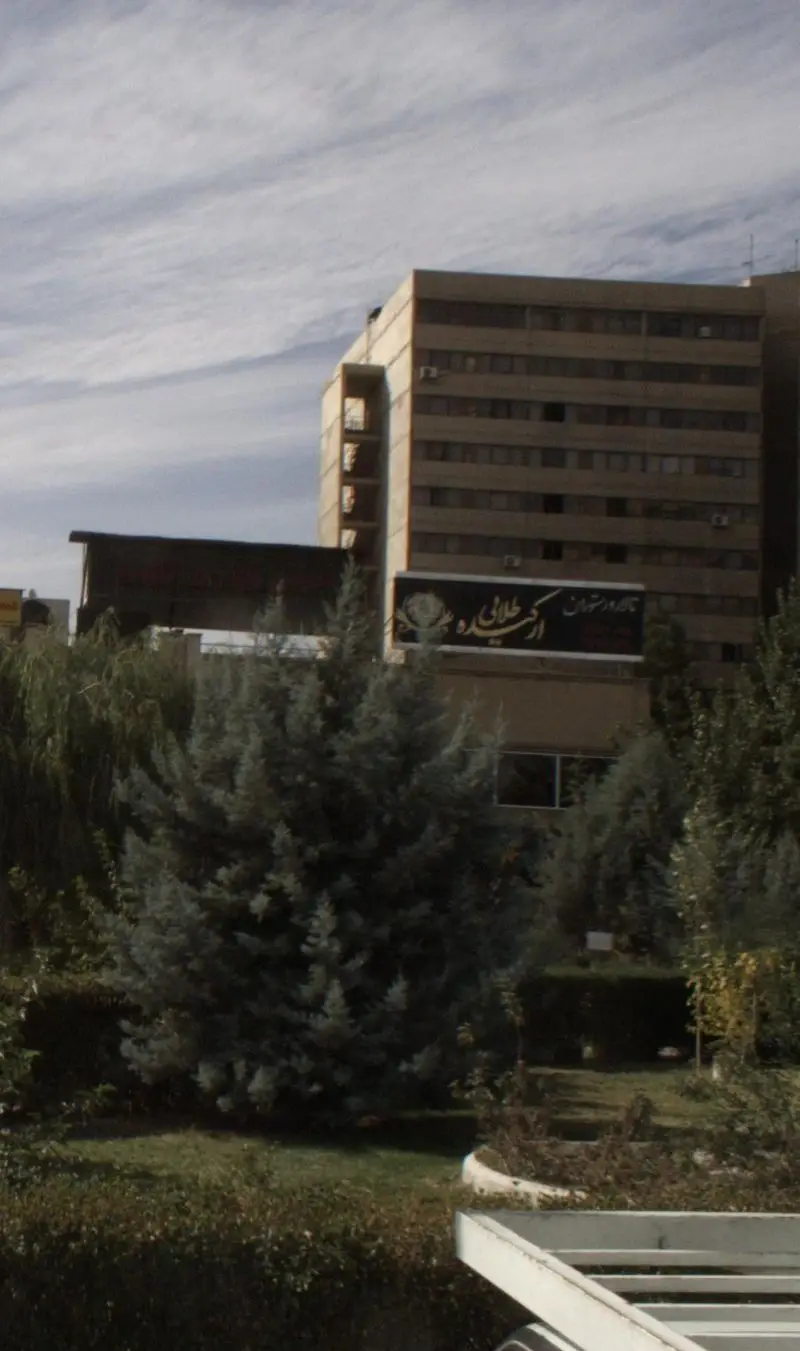 نمای بیرونی و تابلوی رستوران ارکیده طلایی در یک روز روشن، با فضای سبز دلنشین، درختان و ساختمان‌های اطراف در شهر.