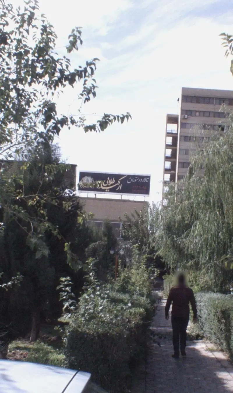 نمایی از ورودی تالار و رستوران ارکیده طلایی با مسیر سنگی در میان فضای سبز دلنشین و ساختمان مجلل در پس زمینه.