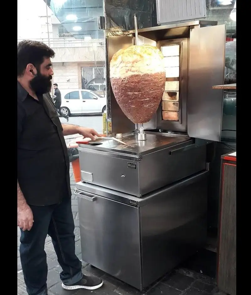 تصویری از آماده سازی و پخت کباب ترکی و دونر کباب در رستوران جوادین. سرآشپز در حال برش گوشت تازه برای شاورما با دستگاه مخصوص.