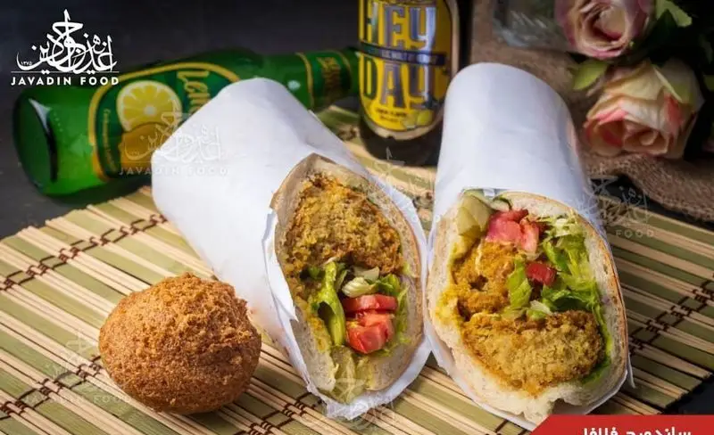 دو ساندویچ فلافل خوشمزه و پرطرفدار جوادین، پر شده با فلافل ترد، گوجه، کاهو و خیارشور تازه، همراه نوشیدنی لیمویی و فلافل اضافی.