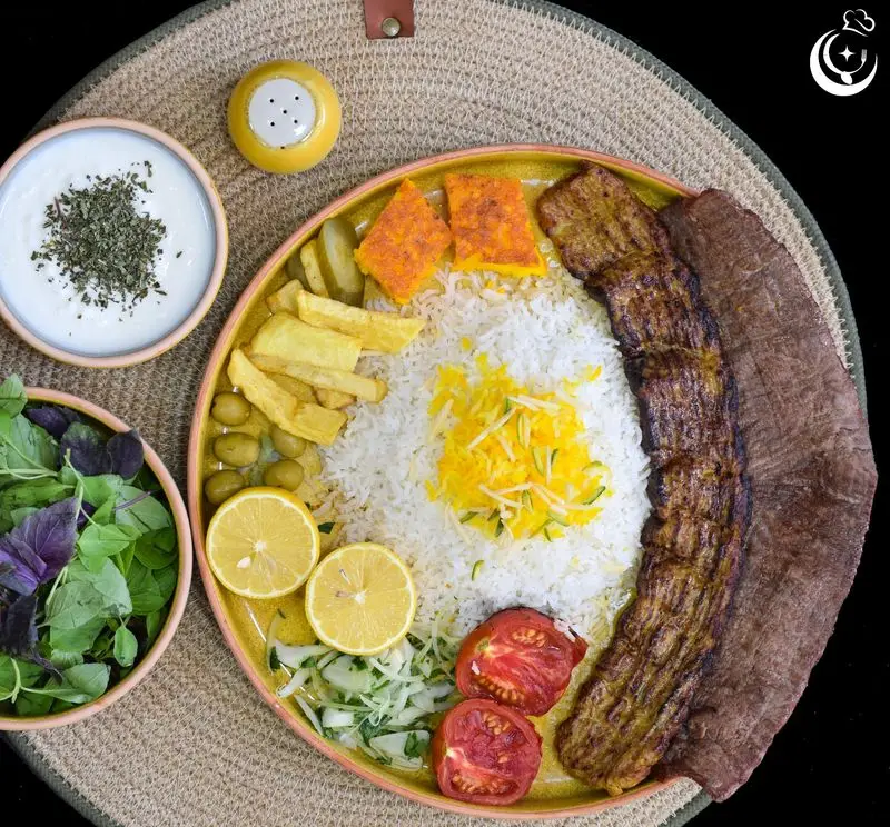 چلوکباب کوبیده و برگ لذیذ رستوران کترینگ آسمان شامل برنج، ته دیگ، سیب‌زمینی، زیتون، سالاد، ماست و سبزیجات تازه.